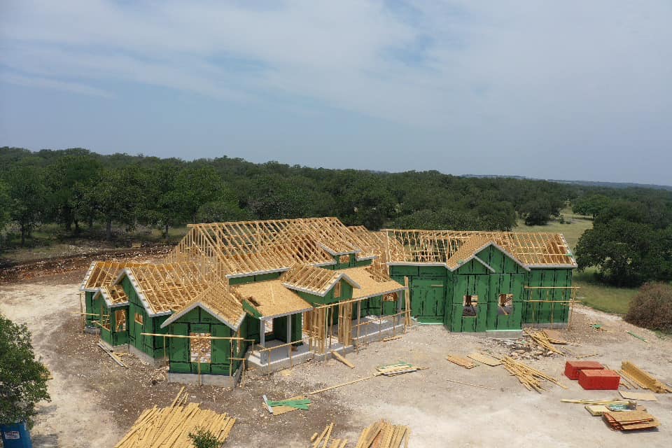 Aerial view of custom home framing in progress on Hill Country lot
