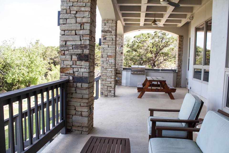 Covered patio with stone columns, outdoor grill, and Hill Country views
